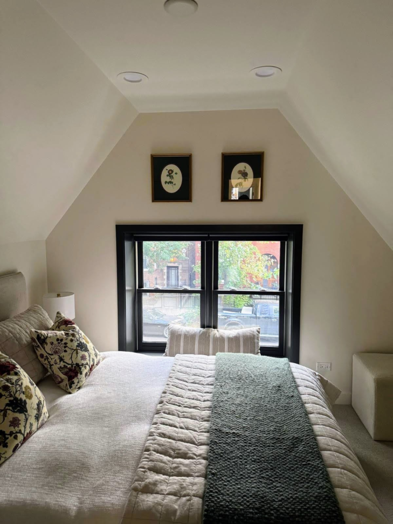 A cozy bedroom paint job with off white walls and dark green trim.